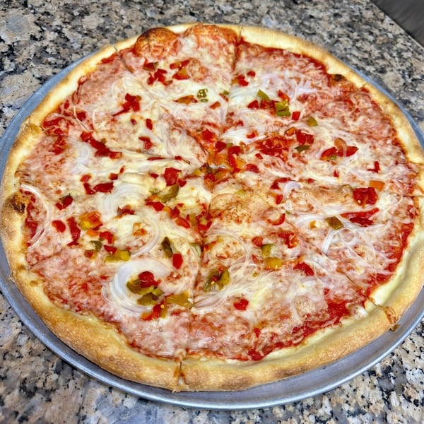 A whole cheese pizza with red and green peppers and onions on a metal pan.