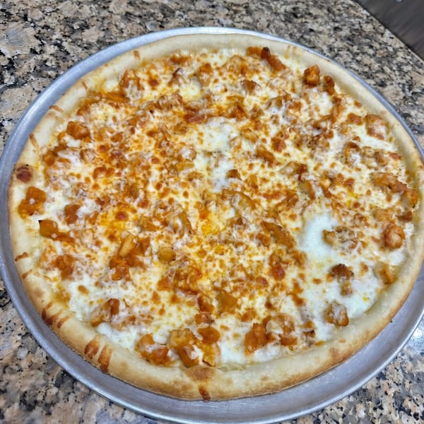 A freshly baked buffalo chicken pizza with white sauce and melted cheese on a metal pan.