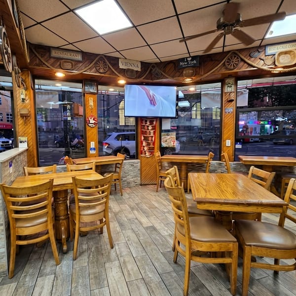 Cozy restaurant interior with wooden tables, chairs, and nautical-themed decor, featuring large windows overlooking a street.