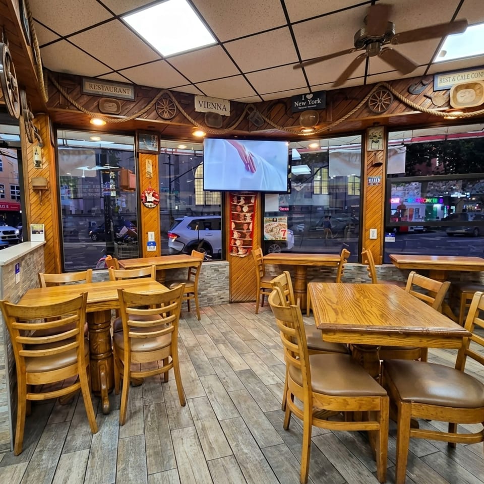 Cozy restaurant interior with wooden tables, chairs, and nautical-themed decor, featuring large windows overlooking a street.